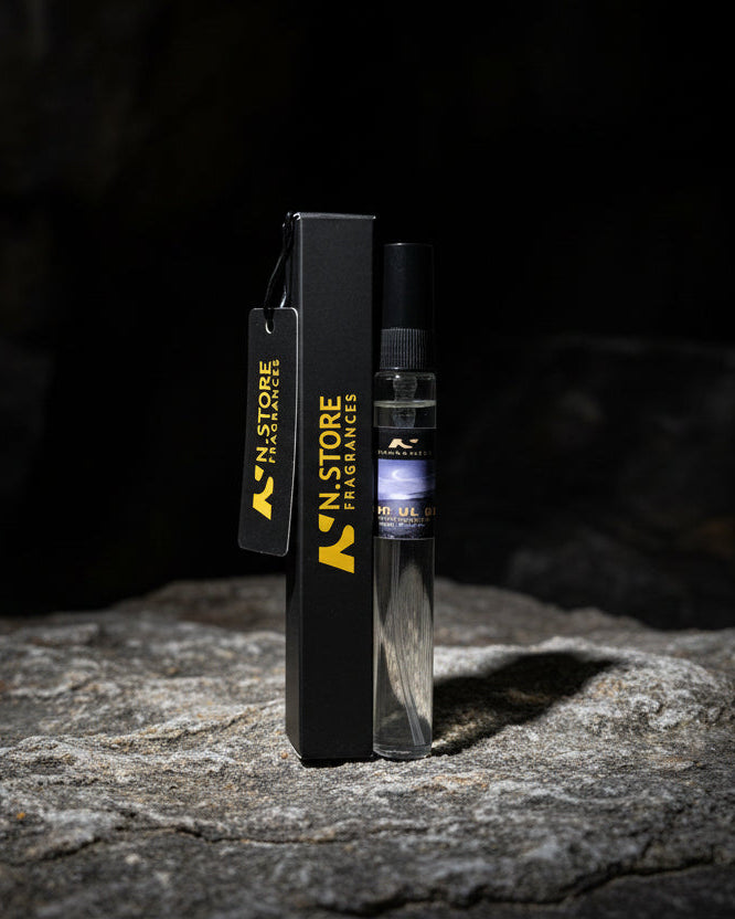 Perfume bottles labeled 'Noor Ul Oud' on a rocky surface with a dark background.